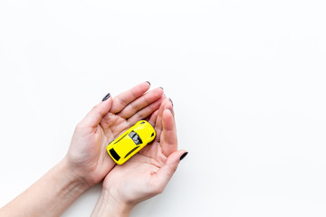 Car insurance concept. Safety of auto. Car toy in female hands on white background top view copy...
