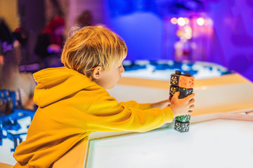 The boy plays with the electronic designer on the light table