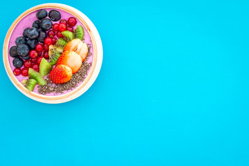 Superfoods. Acai smoothie bowl with fresh fruits, berries, chia seeds on blue background top view copy space