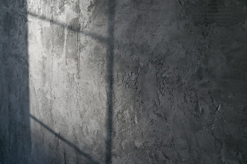 Decorative plaster. Artificial concrete. The texture of the gray concrete wall with a glint of light from the window.