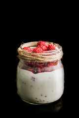 Healthy refreshment breakfast with yogurt, frozen raspberry and chia seeds isolated on black background. Selective focus. Shallow depth of field.