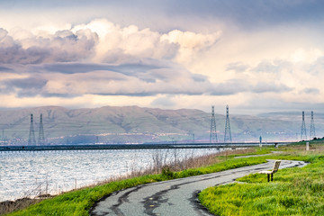 Paved trail following the green grass covered shoreline of south San Francisco bay area, Mountain...