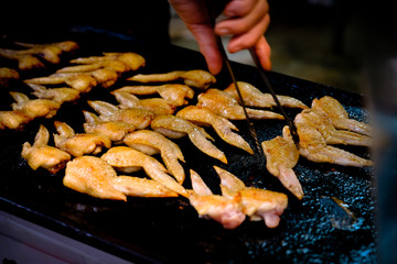 Grilling chicken wings on a black plate cooking over the Barbecue Grill