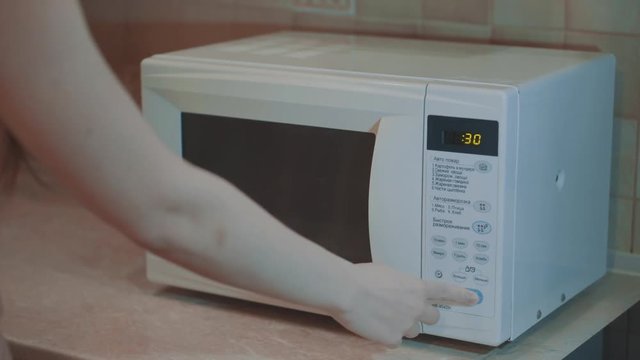 Heated food in the microwave. Female hand puts pies in the microwave in the lunch box. Cooking in the microwave. 4k video.