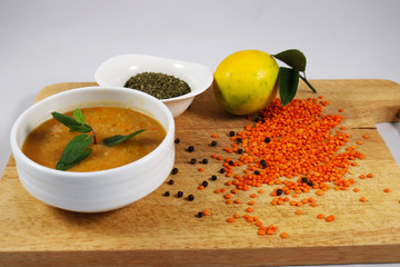 Red lentil soup with lemon on wooden board. lentil, lemon, mint, pepper, pepper grinder. 