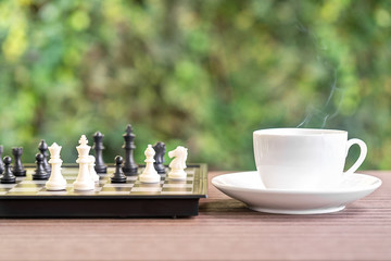 Obraz premium Coffee cup on wood table with Chess board