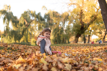 Child playing in the park and autumn leaves