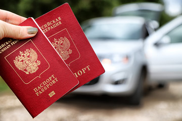 Russian passports in the hand of woman and car background