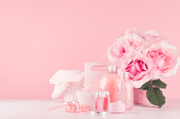 Elegant pink skin and body care products - cream, rose oil, liquid soap, salt, cotton towel and box - cosmetic accessories, romantic flowers on white wood table, copy space.