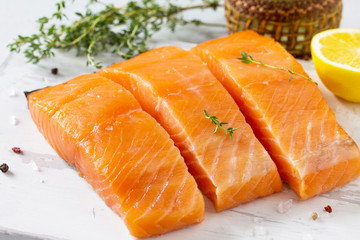 Fresh Fish. Raw Salmon Fillet, Lemon and Spices on a wooden board on a white stone table.
