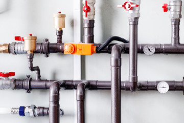 small boiler room in a residential building. metal pipes. There is a pressure sensor and valve.