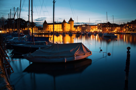 MORGES, SWITZERLAND - March 5th, 2018: Beautiful night time panorama with Morges Castle and boats in the harbour