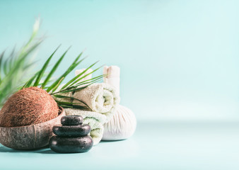 Modern spa setting with coconut and palm leaves. Massage equipment : stack of massage stones,  herbal stamps setting and rolled towels. Healthy lifestyle, beauty  and body care  concept. Copy space