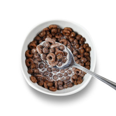 Chocolate cornflakes in a spoon over a plate. Close up. Top view. Isolated on white background