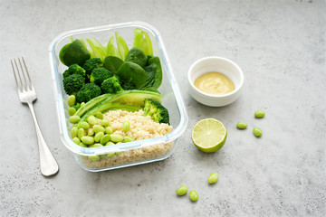 Container with green vegetables and quinoa. Vegetarian lunch with pepper, celery, spinach, broccoli, edamame beans, avocado