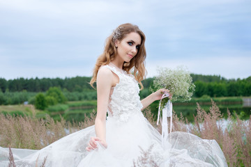 Fototapeta na wymiar Portrait of beautiful young pretty bride in white stylish wedding dress with wedding bouquet in the hand