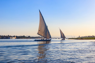 Fototapeta premium Felucca boats sailing on the Nile river in Luxor, Egypt. Traditional Egyptian sailing boats