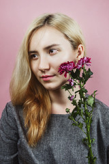 Floral portrait of young adult female with blond hair on pink background