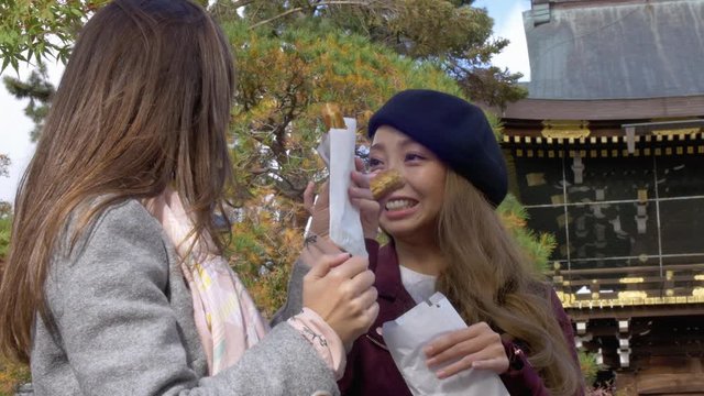 Friends trying Japanese street food in Kyoto temple. 4K