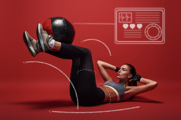 Best exercise. Sportswoman lying over red background, working her abs