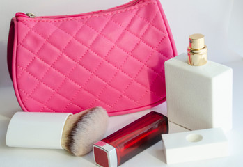white tulip flower. pink cosmetic bag, makeup brushes, cosmetics on white background