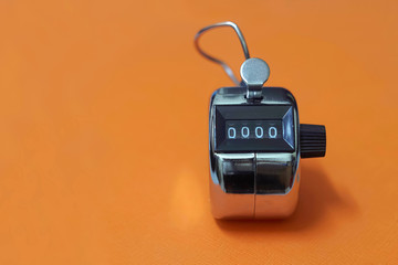 4 digits silver tally counter or hand counter on the orange background