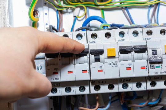 The hand points to a fuse in the power meter. The man disables the current fuses, the safety concept of the power suppression, and the protection of electrical devices
