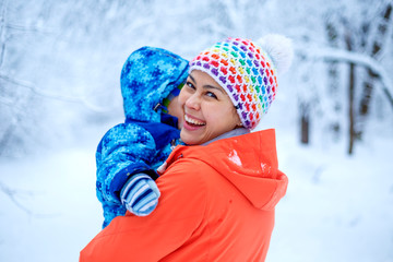 An Asian woman mother and her baby boy are playing in a snowy park in winter