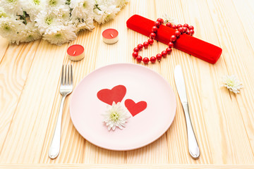 Romantic dinner concept. Valentines day, 8th march or wedding. Table setting, love hearts, gift and flowers. On wooden background
