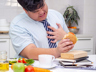 Fat Asian man felling heart pain while he eating food.Man with chest pain suffering from heart attack.