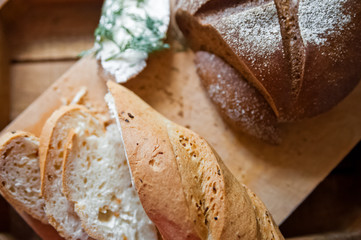 Sliced baguette and round rye black bread. Sandwich with bread, butter and dill. White loaf and rye bread close up and copy space