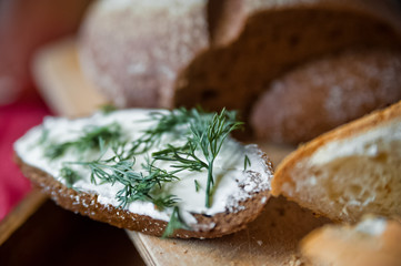 Sliced baguette and round rye black bread. Sandwich with bread, butter and dill. White loaf and rye bread close up and copy space