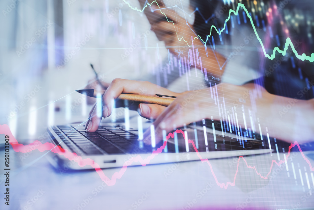 Wall mural hands typing on laptop. business and financial concept. double exposure of stock market charts.