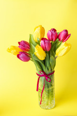 Bouquet of yellow and pink tulips on a yellow background.