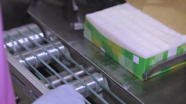 Sugar in packs on the conveyor in the factory