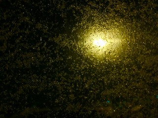 snow flakes night time with yellow lamp