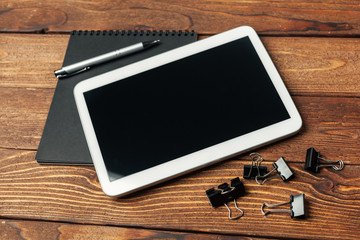 Tablet with notepad on wooden background