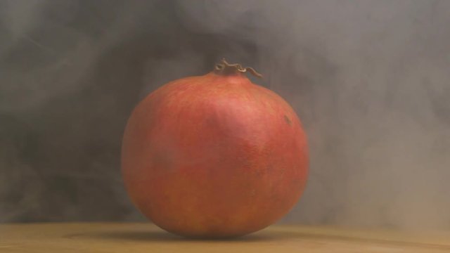 Ripe rotating pomegranate fruit from which evaporation and freshness are on a black background, close-up, slow motion
