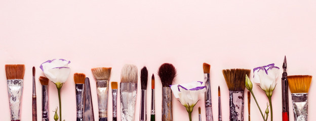 Art pink background. Row of different brushes and flowers. Banner format