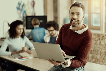 Bearded man in a brown sweater smiling brightly