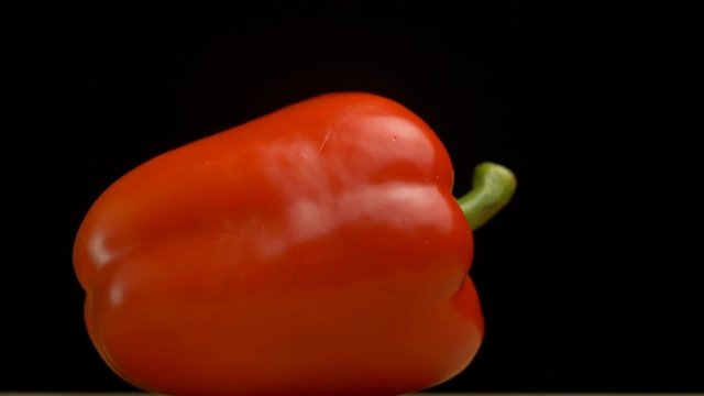 Juicy red Bulgarian pepper on a black background, natural vegetable, close-up, slow motion