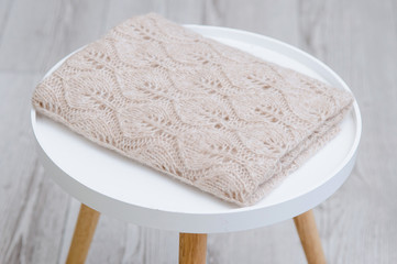 StA stack of knitted handmade plaids is lying on a tabouretack of knitted plaids made by hand