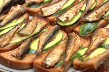 Sprats with cucumber slices on toasted bread, close-up