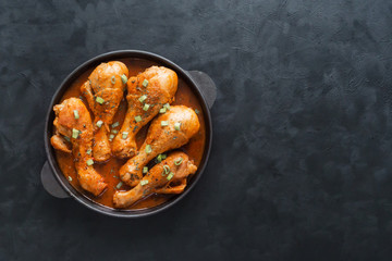Fried chicken legs with curry in an cast iron pan.
