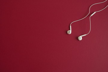 Directly above shot of white earphones on red background