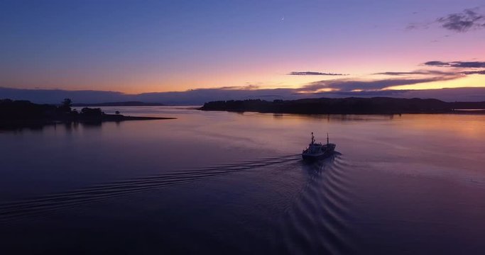 Aerial view with drone of a boat sailing through the Chilo&eacute; archipelago before sunrise