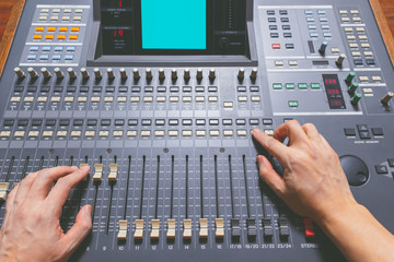 sound engineer hands working on sound mixing console in recording studio. music production, broadcasting concept