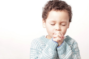 boy praying to God with hands held together