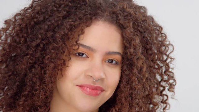 mixed race black woman with freckles and curly hair closeup portrait making faces. Surprised model lift up her brow and then smiling and watching aside
