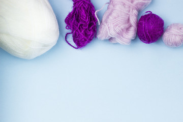 Products for needlework, knitting. Balls of pink, purple yarn on a blue background. Space for text.